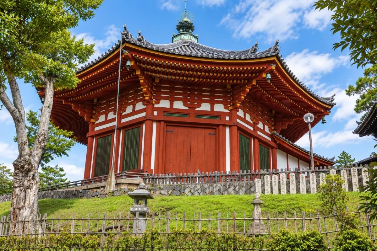 Octagonal temple pavilion in Nara with red wooden architecture and stone lanterns